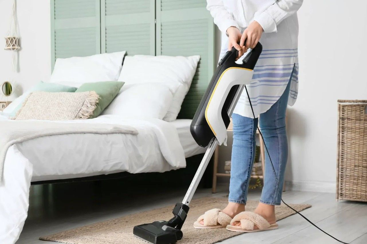 Cleaner vacuuming a tidy bedroom during a recurring visit