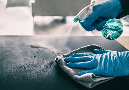 Sanitizing a desk surface with disinfectant spray